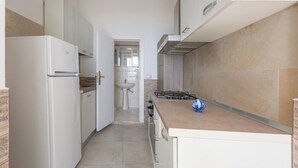 Eine schmale Küche mit Kühlschrank, Herd und Spüle.