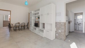 Eine moderne Küche mit weißen Schränken, einem Essbereich mit Stühlen und einem sichtbaren Spülbecken.