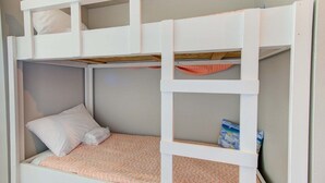 Un lit superposé composé d’un lit inférieur et d’un lit supérieur, tous deux dotés de structures blanches et d’un matelas à motifs roses.