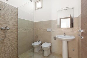 A modern bathroom with a glass shower enclosure, a white sink, and two toilets. - Nella Suites - Bilo PT (Porto Cesareo)