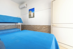 A room with bunk beds, a wardrobe, and a wall-mounted air conditioner. - Nella Suites - Bilo PT (Porto Cesareo)