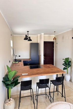 Una cocina moderna con una isla de madera, taburetes negros y luminarias colgantes.