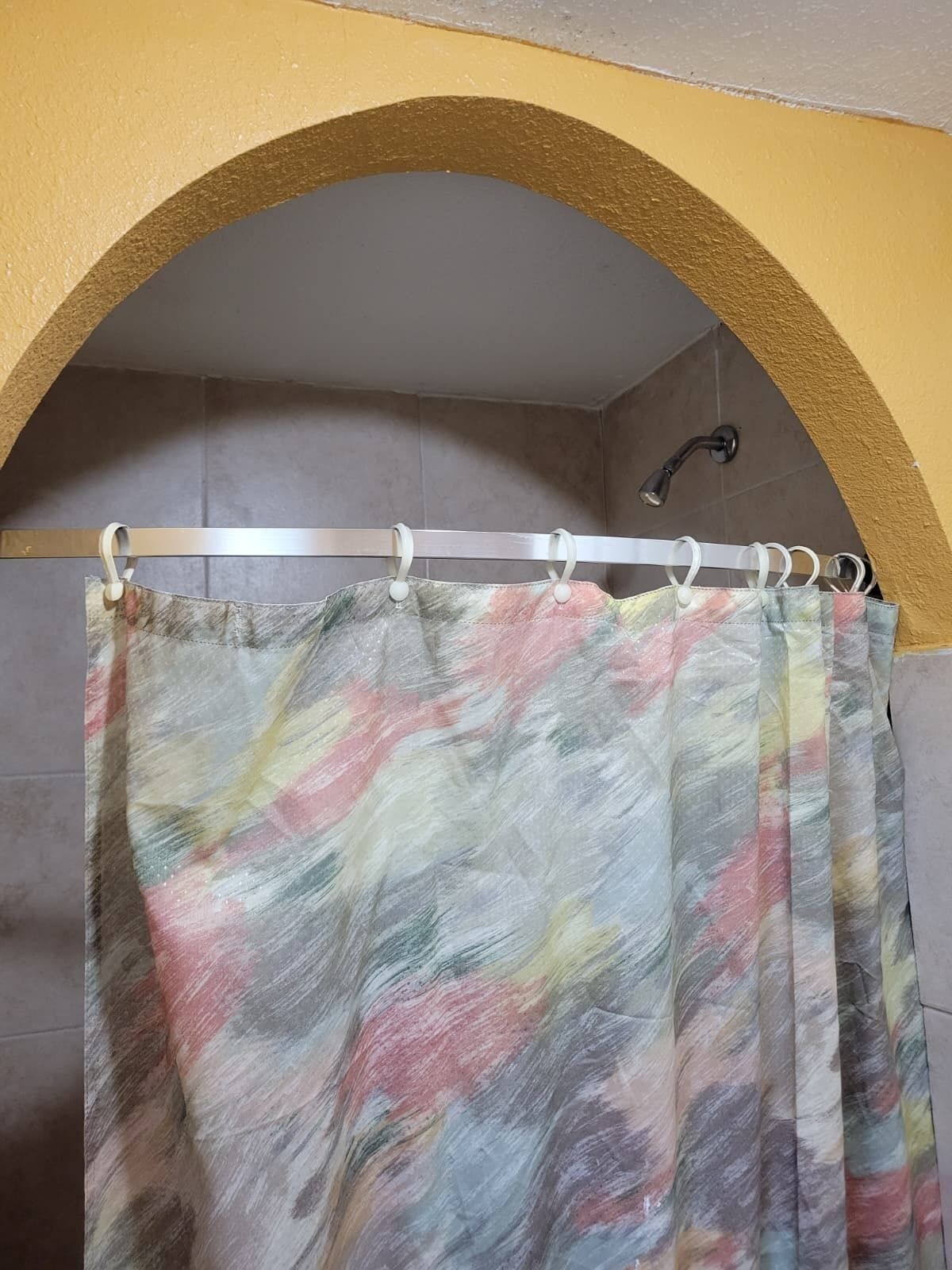 A bathroom with a shower curtain, a towel rack, and a showerhead.