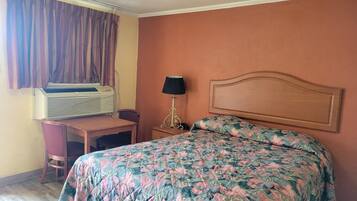 Una habitación de hotel con una cama, un escritorio, una lámpara y un equipo de aire acondicionado.