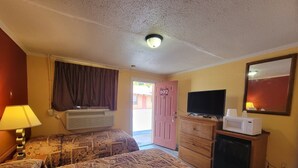 A hotel room with two beds, a television, a microwave, a dresser, and a door marked with the number 102. - Relax Inn Daingerfield Near Mount Pleasant TX (Daingerfield)