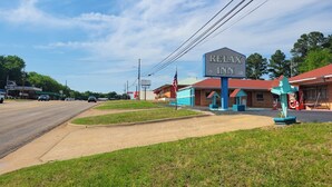 A motel with a large sign, a parking lot, and a grassy area. - Relax Inn Daingerfield Near Mount Pleasant TX (Daingerfield)