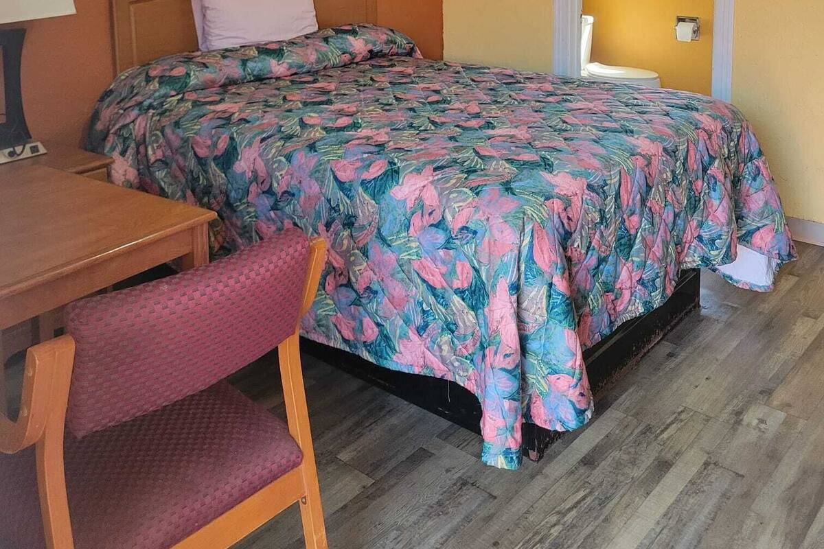 Una habitación con una cama, un escritorio y una silla.
