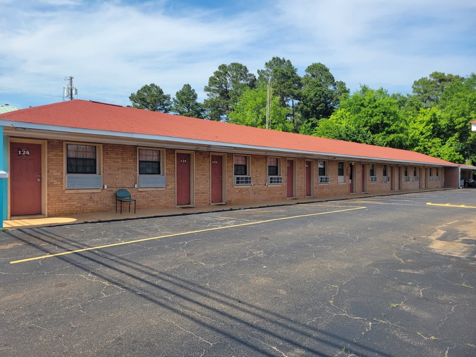 A motel with a red roof, numbered rooms, and a parking lot.