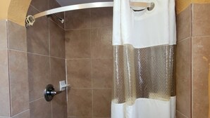 A shower with a curved shower curtain, tiled walls, and a metallic handle. - Relax Inn Daingerfield Near Mount Pleasant TX (Daingerfield)