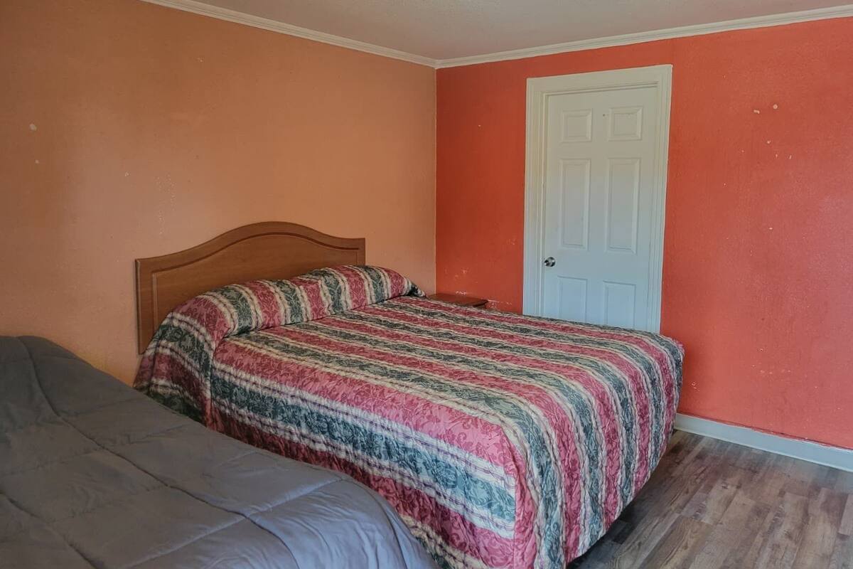 Un dormitorio con una cama, una puerta y una lámpara en el techo.