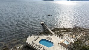 A waterfront property with a swimming pool, lounge chairs, and a dock extending into the water. - Oceanfront Retreat on Spruce Point, Private Dock, Hot Tub & Resort Amenities (Boothbay Harbor)