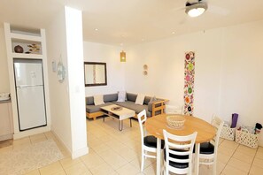 A compact living space with a kitchenette, a sofa, a dining table with chairs, and a colorful curtain. - VVII42 Relaxing Tropical Condo in Amazing Location (Tamarindo)