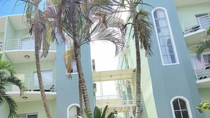 Een meerlaags gebouw met balkons, palmbomen en een centraal atrium.