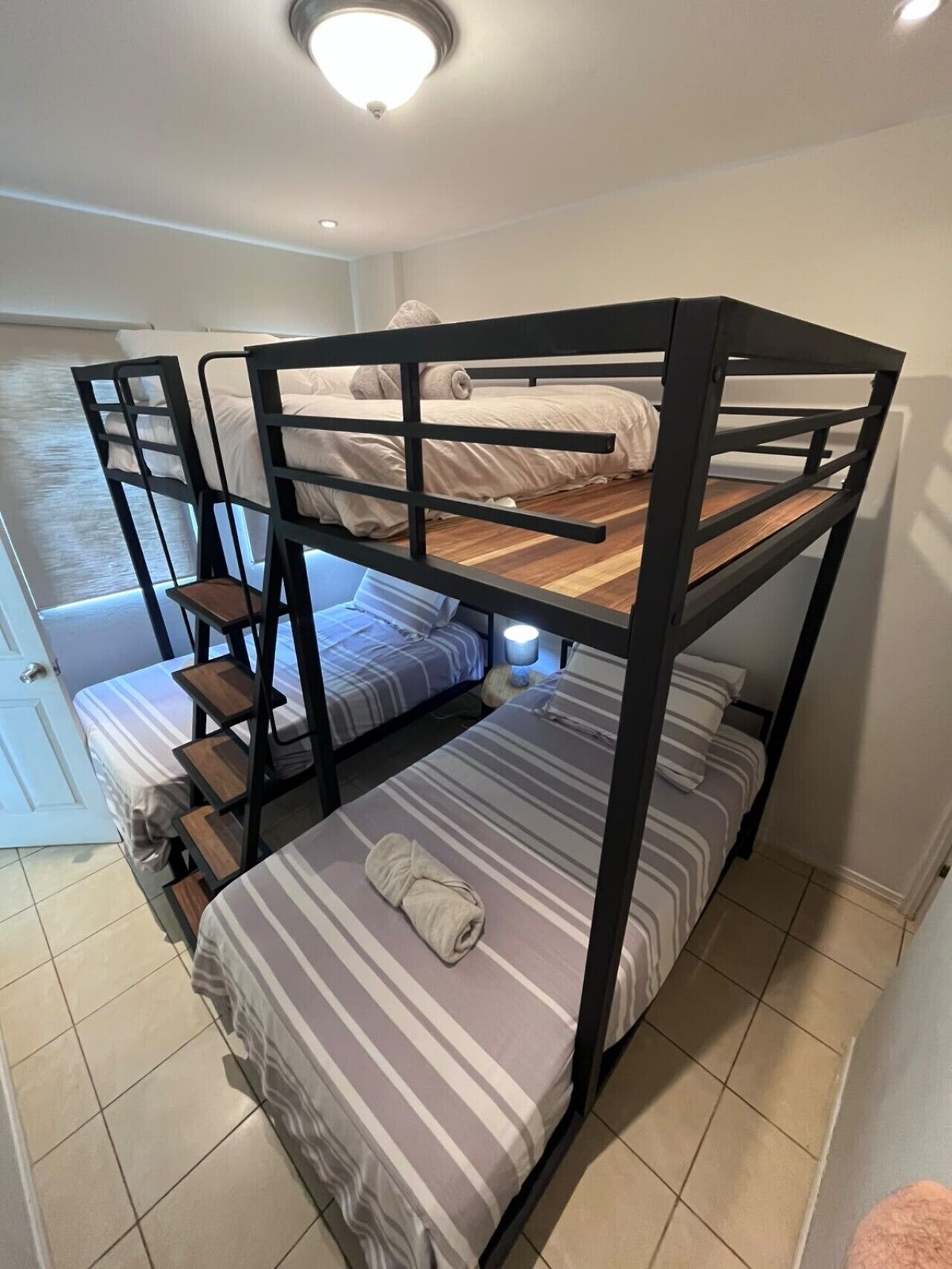 Habitación con literas, ventana, puerta y escalera.