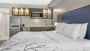 Ein Hotelzimmer mit einem Bett, einer integrierten Mikrowelle, einem Kühlschrank, einem Waschbecken und einem Schrank.