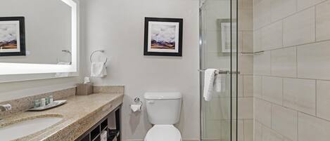 A bathroom with a sink, toilet, and glass shower enclosure.