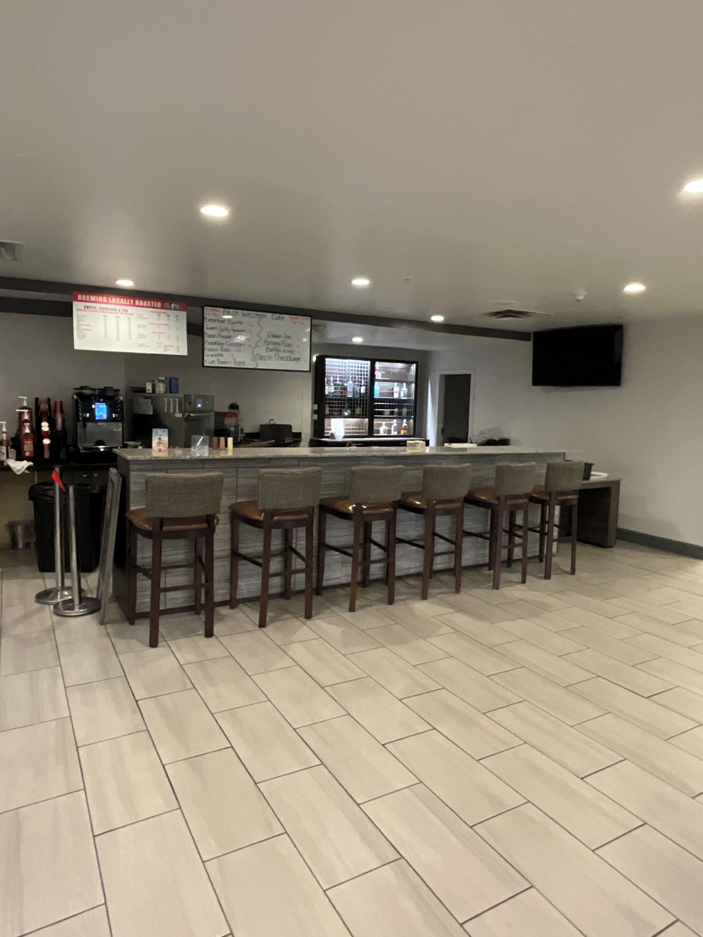 A bar area with a counter, stools, and a menu board.