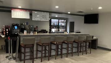 Uma área de bar com balcão, banquetas e um quadro de menu.