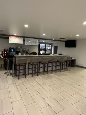 A bar area with a counter, stools, and a menu board.