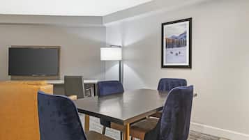 A conference room with a large table, four chairs, a television, and a lamp.