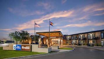 Un bâtiment moderne doté d’un espace extérieur couvert avec des sièges, d’un mât portant le drapeau américain et d’une enseigne indiquant « Best Western Executive Residency ».