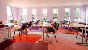 A conference room with multiple tables and chairs, large windows, and a colorful carpet. - Best Western Hotel Altenburger Land (Altenburg)
