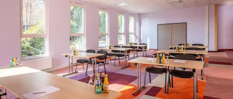 Une salle de conférence équipée de plusieurs tables, de chaises et d’un tableau blanc.