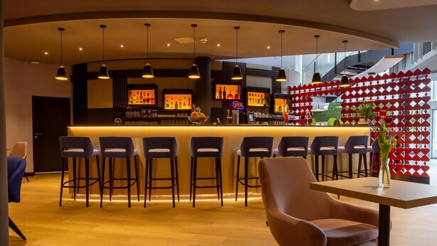 A bar area with stools, a counter, and a decorative red wall. - Best Western Hotel Altenburger Land (Altenburg)