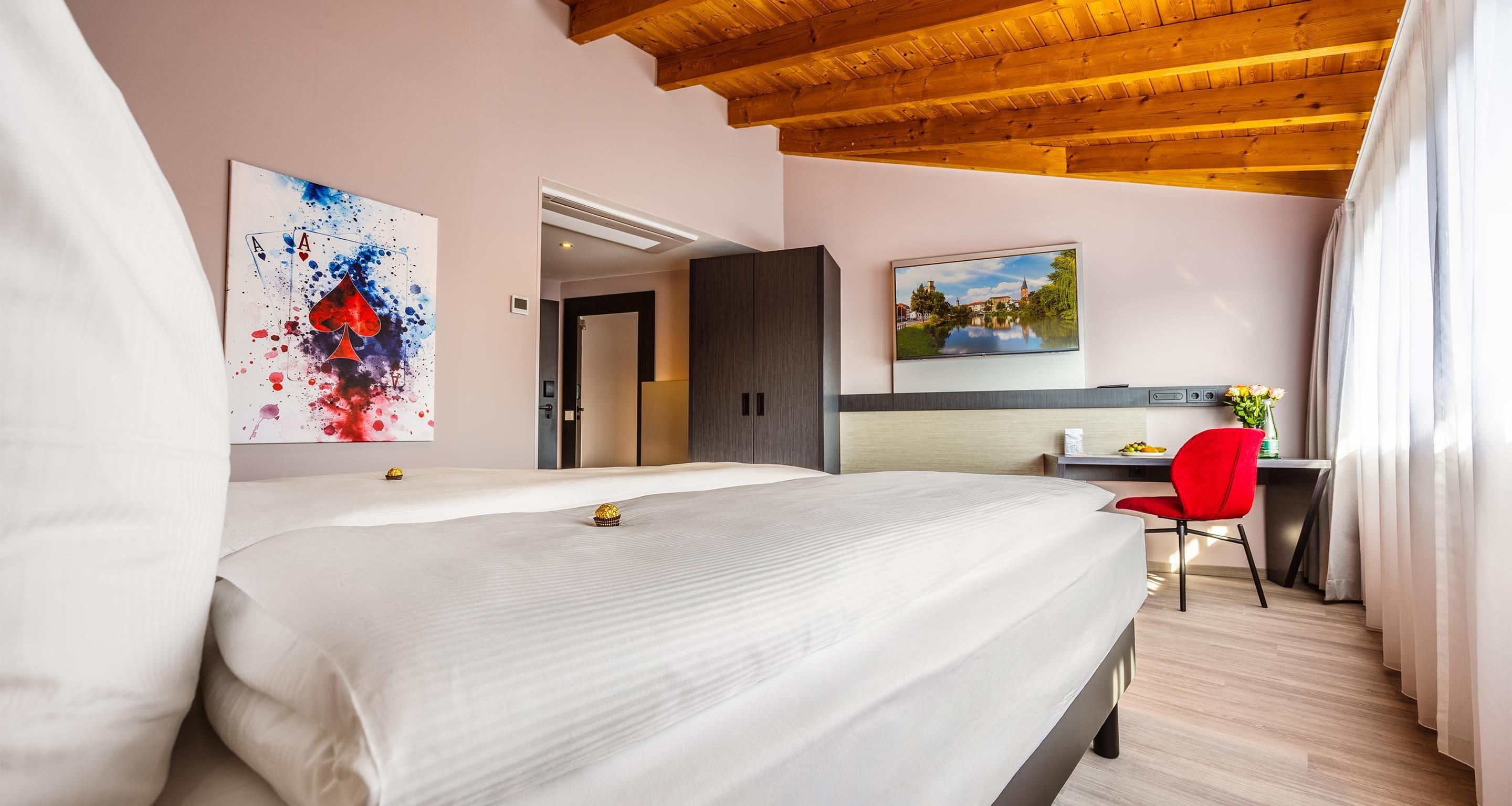 Una habitación de hotel con cama, escritorio, silla y obras de arte en las paredes.