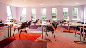 A conference room with multiple tables and chairs, large windows, and a colorful carpet. - Best Western Hotel Altenburger Land (Altenburg)