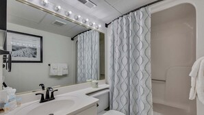 Un baño con lavamanos, espejo, cortina de ducha e inodoro.