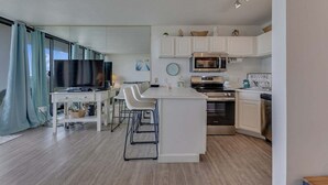 Una cocina moderna con armarios blancos, una isla central, microondas integrado y estufa.