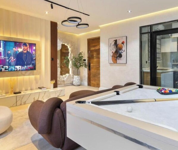 A modern living room with a pool table, a television, and a seating area. - Opulence Reality Stays (Lagos)