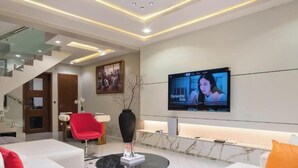 A modern living room with a TV, sofas, a coffee table, and a staircase. - Opulence Reality Stays (Lagos)