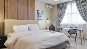 A modern hotel room with a large bed, a small table, and a chair. - Opulence Reality Stays (Lagos)
