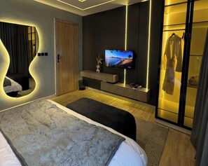 A modern bedroom with a bed, a TV, a mirror, and a wardrobe. - Opulence Reality Stays (Lagos)