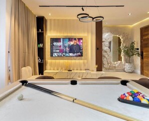 A modern living room with a pool table, a large flat-screen TV, and a stone accent wall. - Opulence Reality Stays (Lagos)