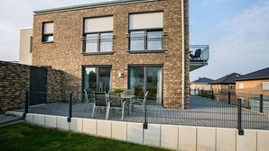 Un bâtiment moderne à deux étages, doté d’une façade en briques, de grandes fenêtres et d’un balcon.