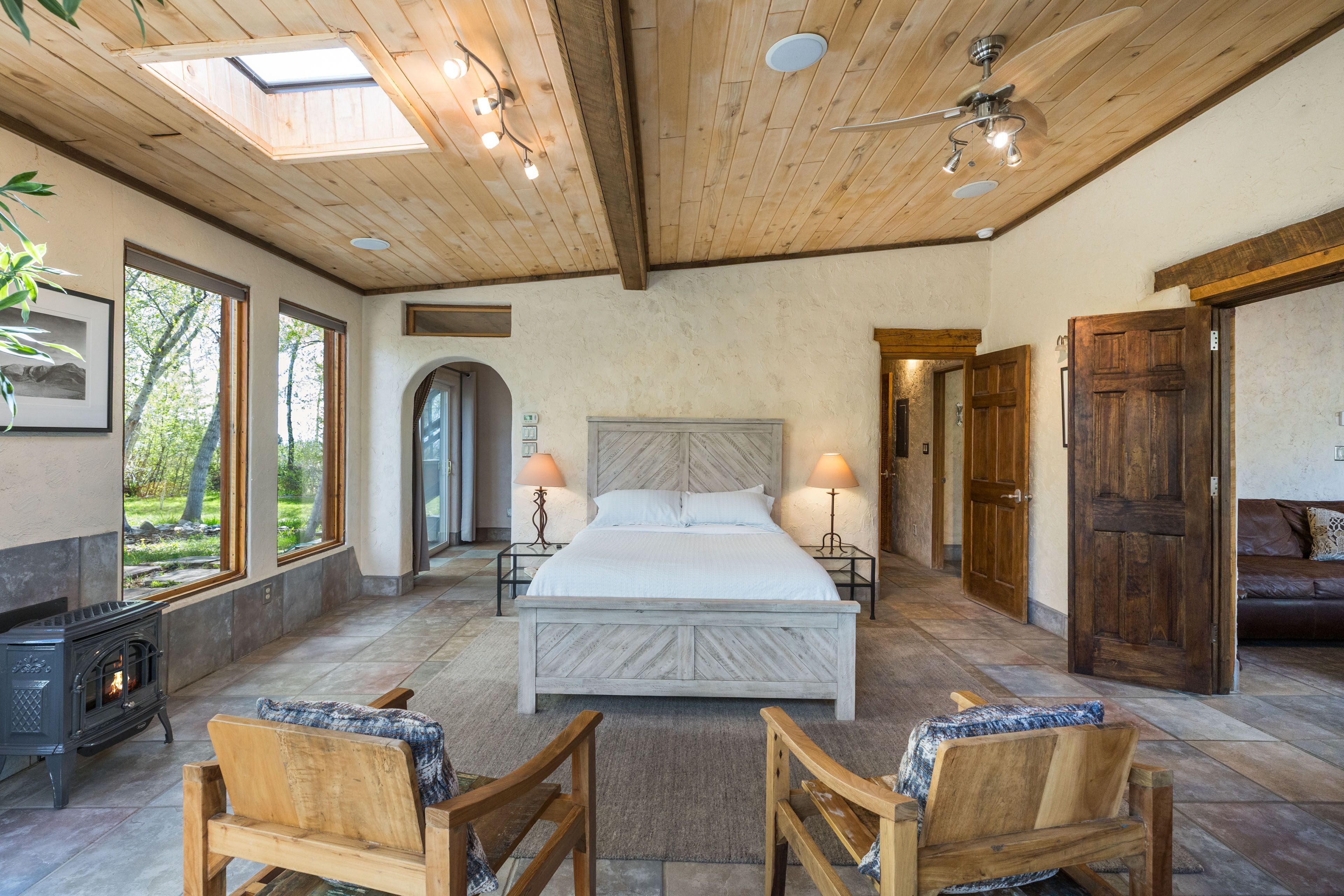Un dormitorio con una cama grande, techo de madera y chimenea.