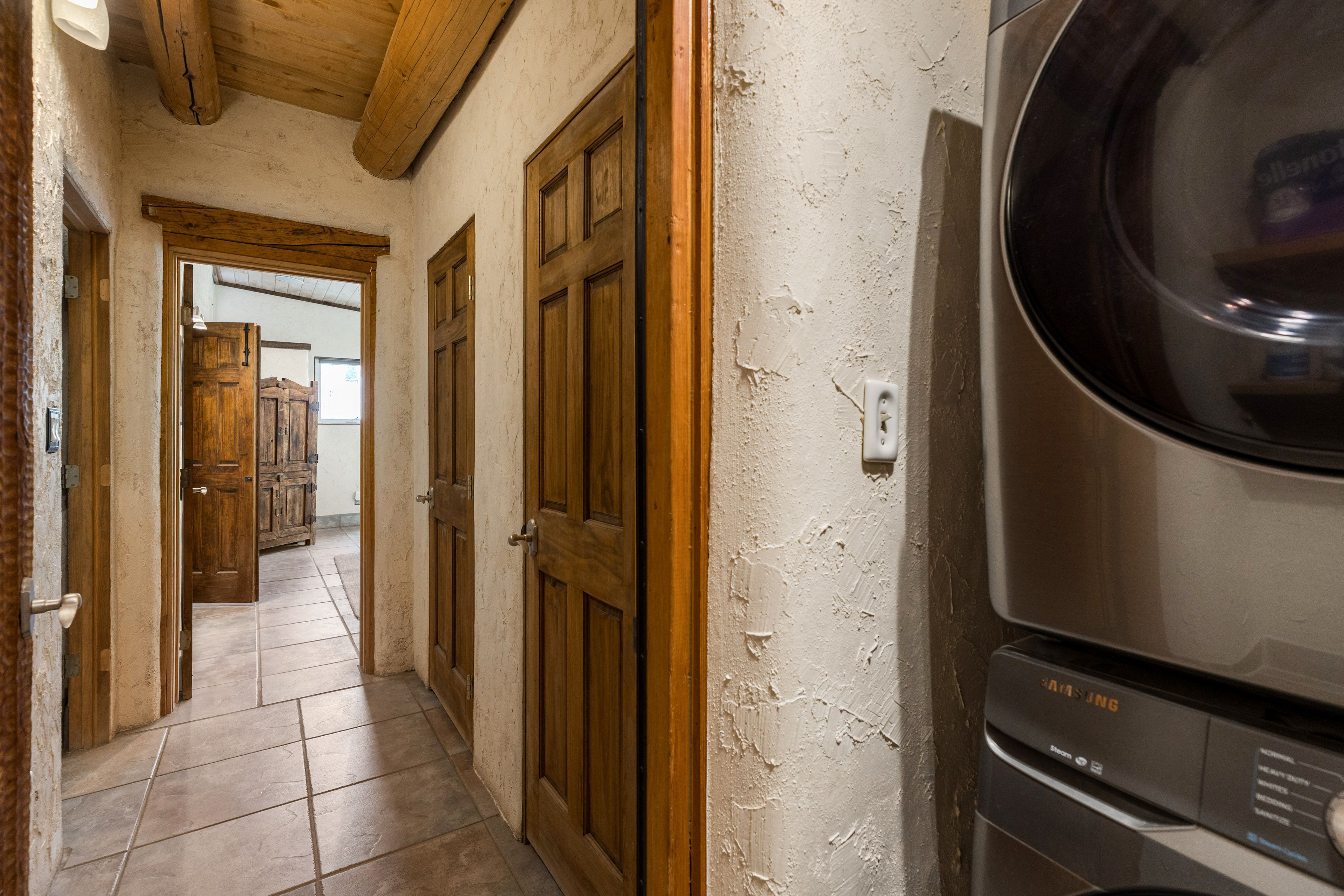 A laundry room with a washing machine, wooden doors, and a tiled floor.
