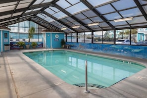 An indoor swimming pool with a glass ceiling, a mural of marine life, and a bench. - Enjoy oceanfront bliss at 0208 Tiki Tower (Carolina Beach)