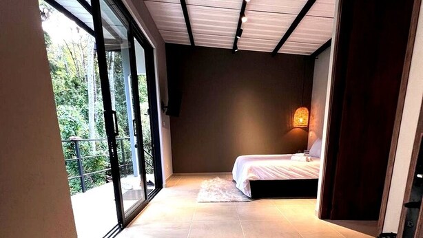 Un dormitorio con cama, mesita de noche, ventana y puerta.