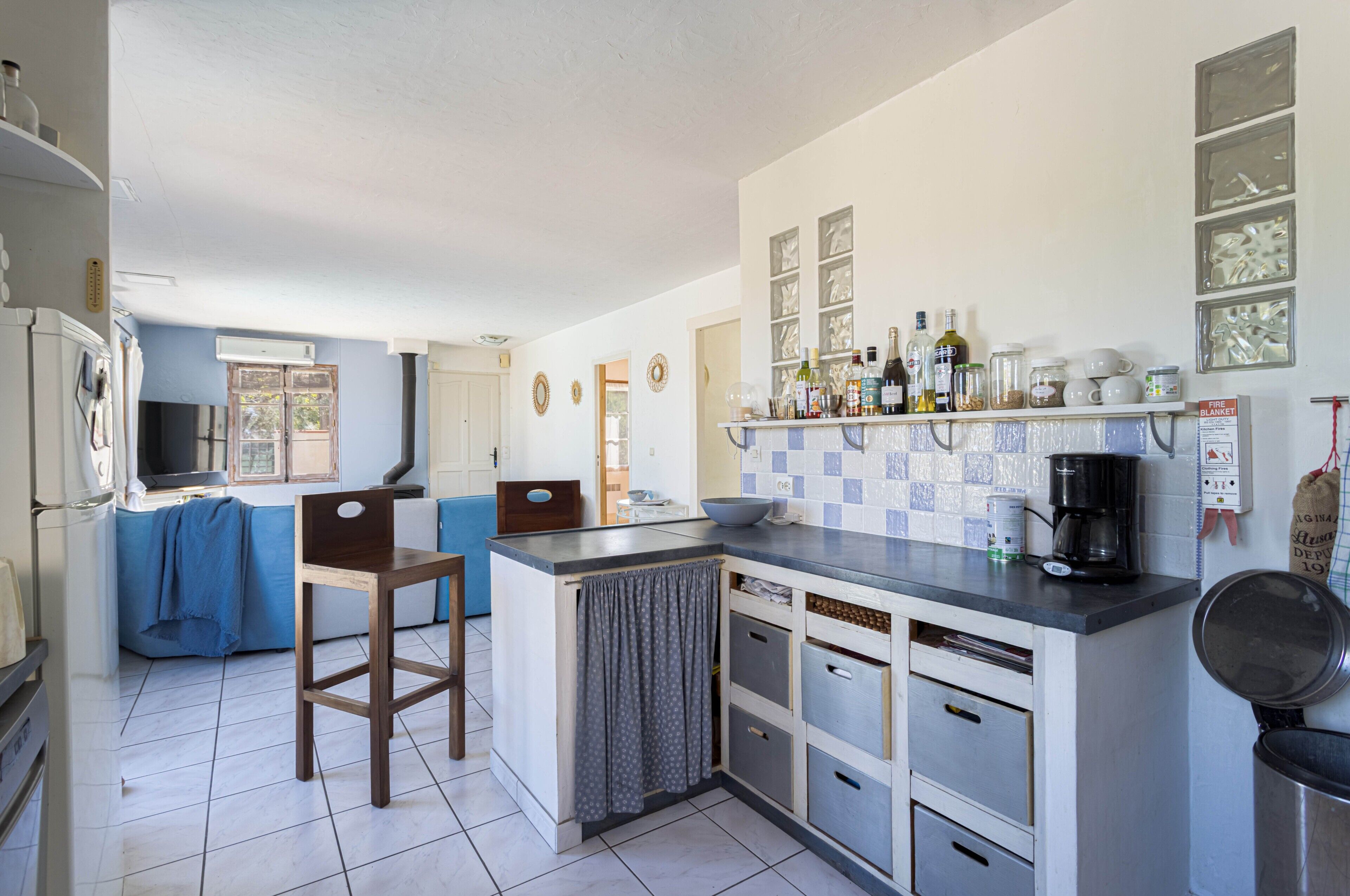 A compact kitchen with a central island, a coffee machine, and a variety of storage cabinets.