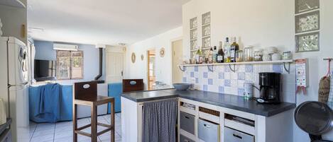 A compact kitchen with a central island, a coffee machine, and a variety of storage cabinets.