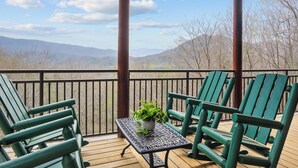 A wooden deck with green chairs and a table, overlooking a mountainous landscape. - Luxury Views and Prime Smoky Mountain Location (Sevierville)