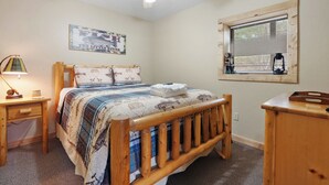 A bedroom with a wooden bed, a nightstand, a lamp, a window with blinds, and a ceiling fan. - Luxury Views and Prime Smoky Mountain Location (Sevierville)