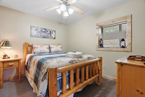 A bedroom with a wooden bed, a nightstand, a lamp, a window with blinds, and a ceiling fan. - Luxury Views and Prime Smoky Mountain Location (Sevierville)