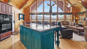 A spacious kitchen with a large island, wooden ceiling, and a view of mountains through large windows. - Luxury Views and Prime Smoky Mountain Location (Sevierville)