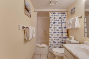 Een badkamer met een bad, toilet en douchegordijn met een visjesprint.