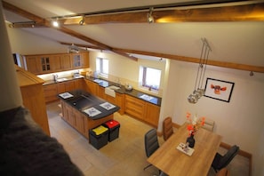A kitchen with wooden cabinets, a central island, and a dining area with a table and chairs. - Meadow View Aysgarth (Aysgarth)
